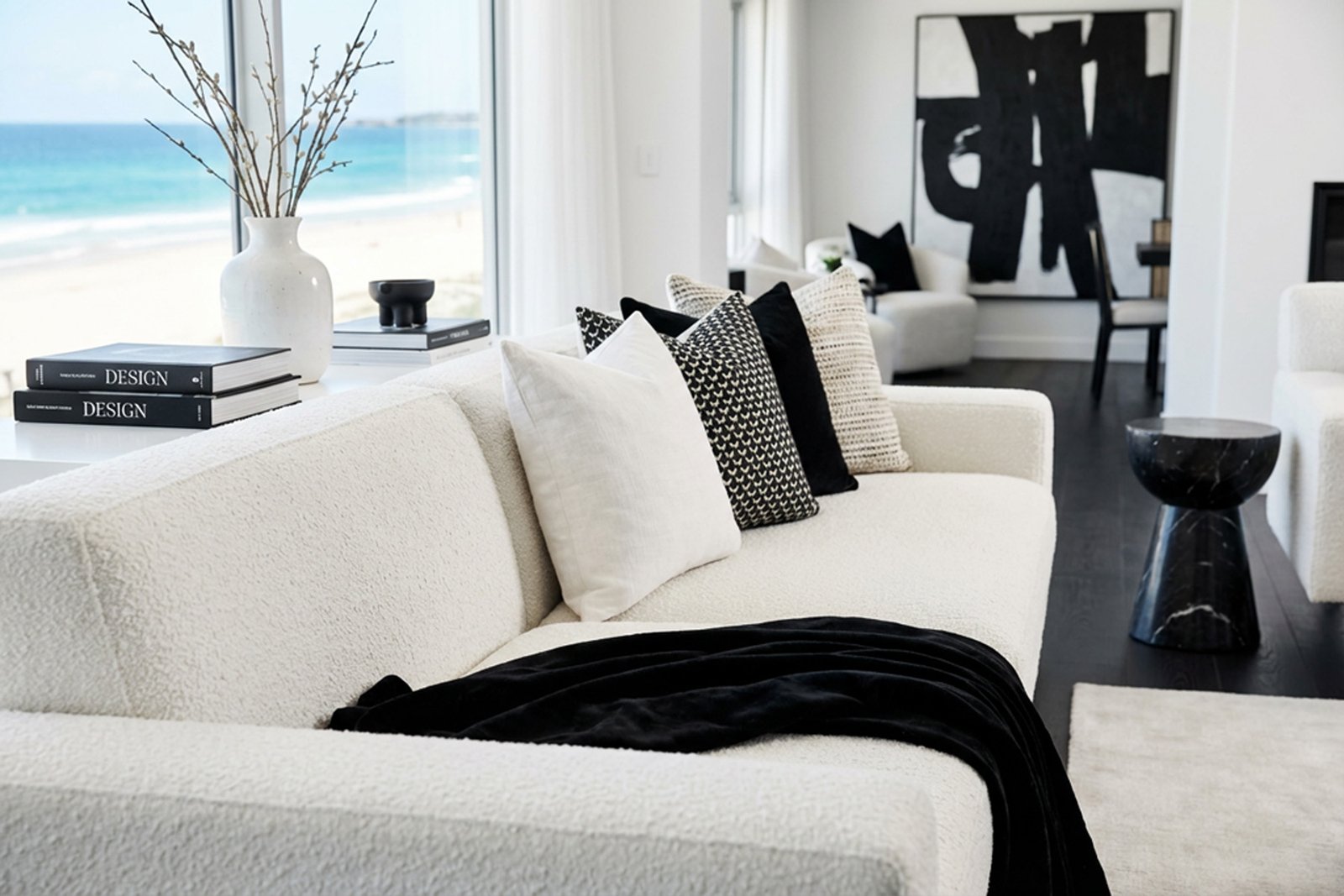 A white bouclé sectional with black accents and an ocean view